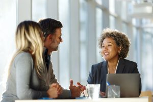 Happy female agent talking to a couple in the office.